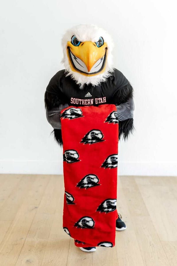 Southern Utah Thunderbirds mascot holding red Minky blanket with eagle logos.