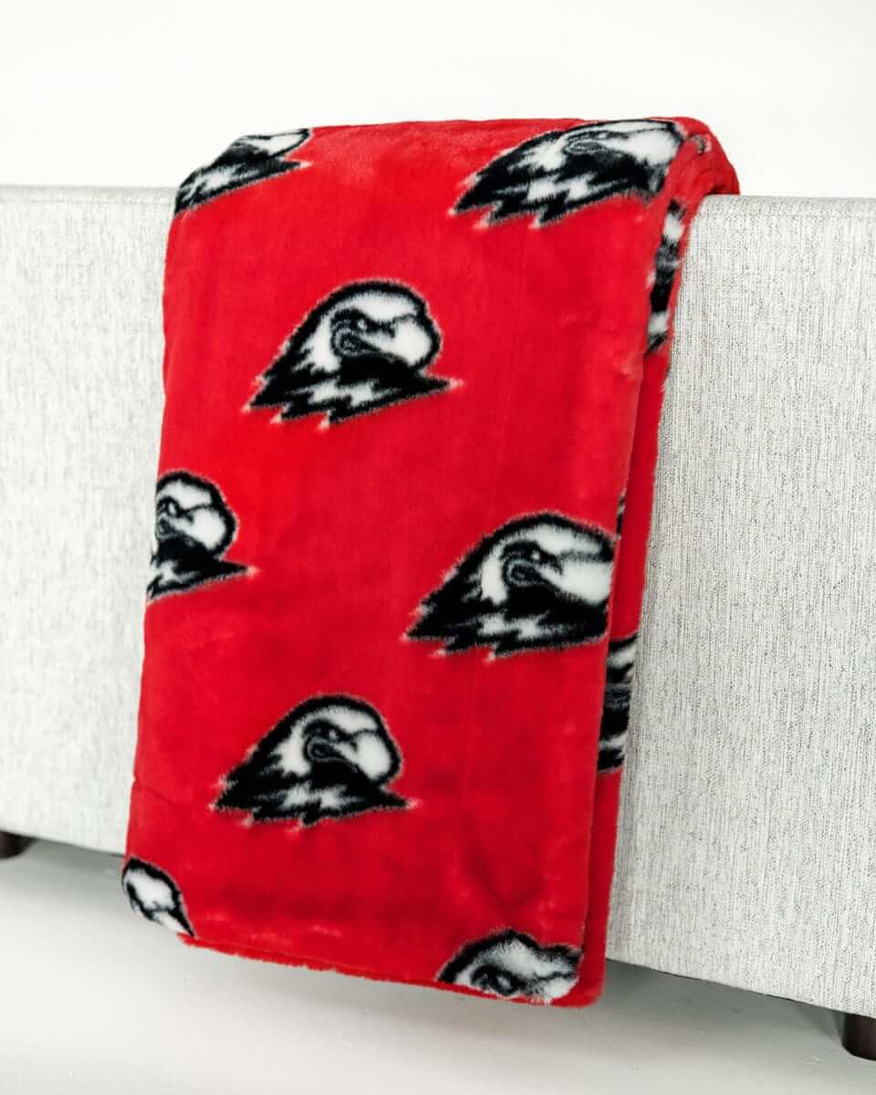 Red Southern Utah Thunderbirds blanket draped over light gray sofa.