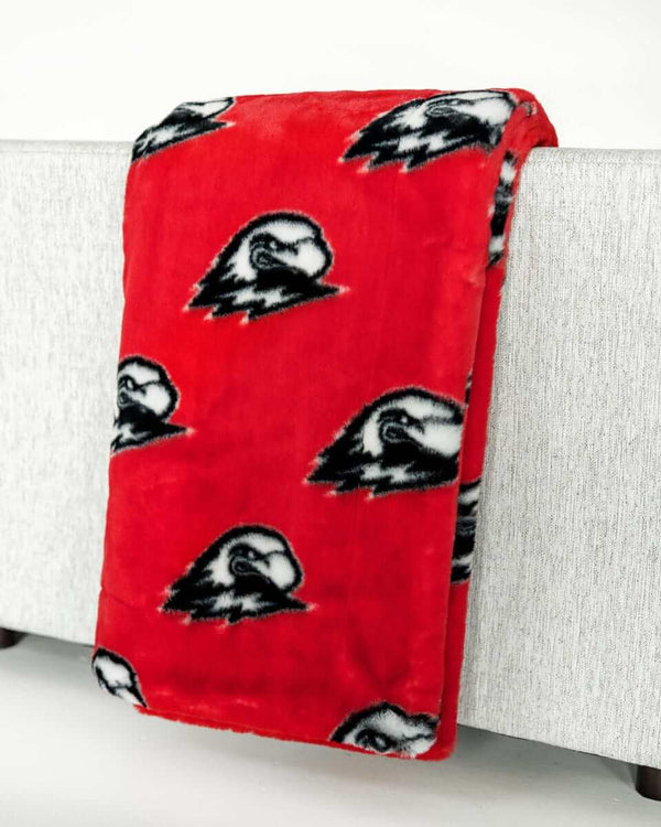 Red Southern Utah Thunderbirds blanket draped over light gray sofa.