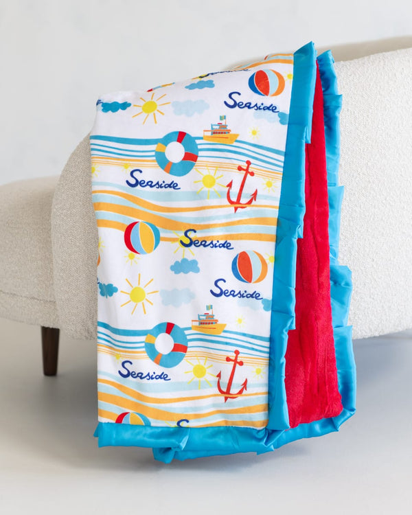 Colorful beach-themed blanket with red, blue, and white colors on a couch.