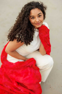 Model showcasing the Sorbet Red Blanket, a silky smooth and vibrant blanket perfect for warm seasons.