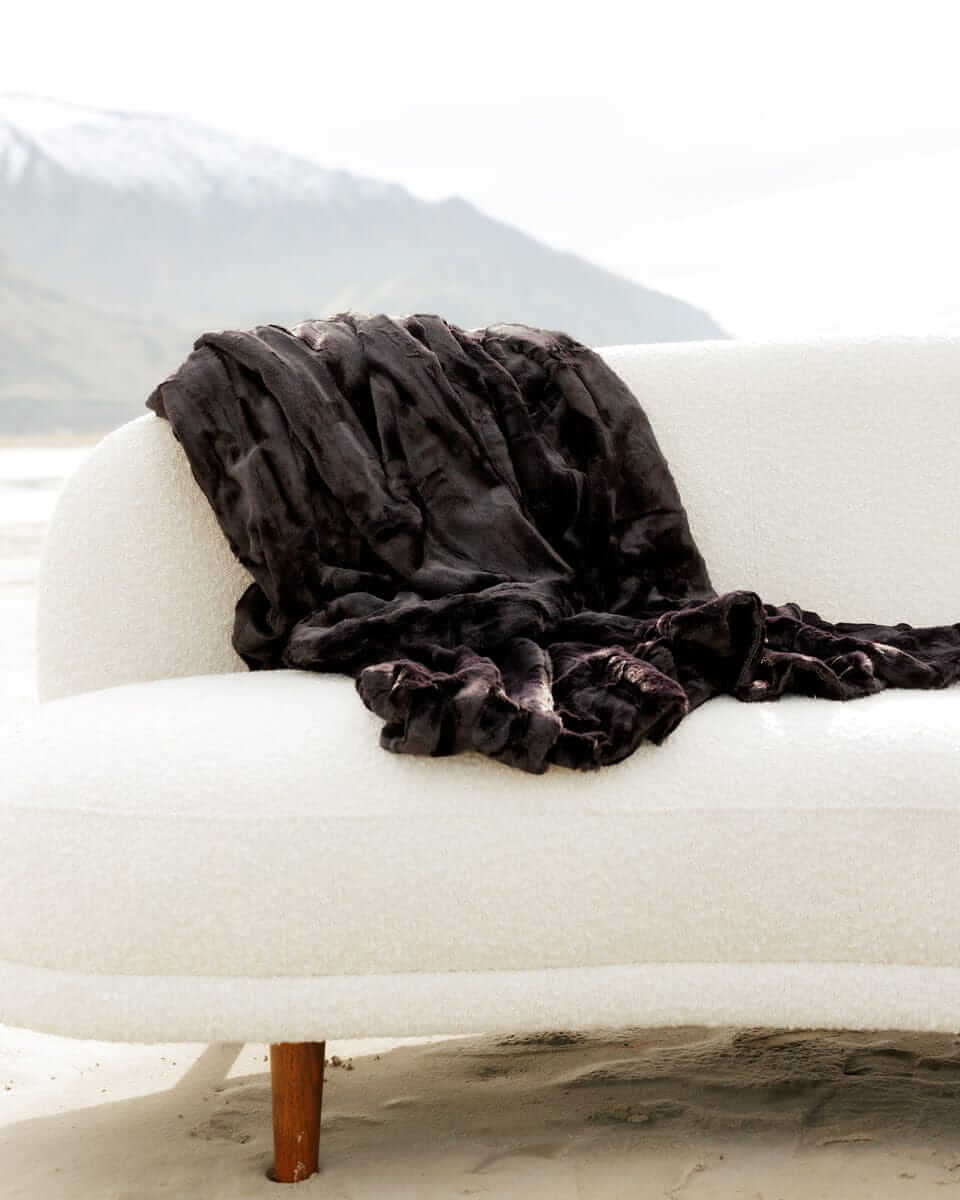 Sleek Sorbet Black Blanket draped on a cozy white sofa, showcasing its elegance and versatility.