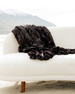 Sleek Sorbet Black Blanket draped on a cozy white sofa, showcasing its elegance and versatility.