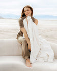 Woman relaxing on a couch, holding a Sorbet Vanilla Blanket for travel and warm weather comfort.