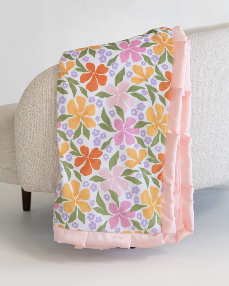 Floral-patterned blanket draped over a chair with a light background.