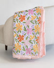 Floral-patterned blanket draped over a chair with a light background.