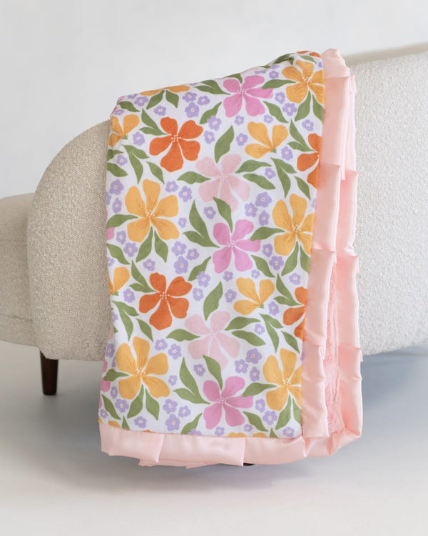 Floral-patterned blanket draped over a chair with a light background.