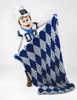 A Dallas Cowboys mascot in a white cowboy hat and football uniform holds up a large plush throw blanket with a blue and gray argyle pattern against a white studio background.