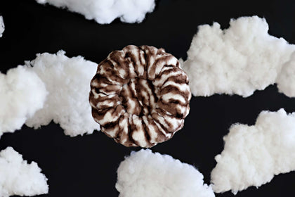 Minky Couture Cloudy Day Brown Pet Bed surrounded by fluffy white clouds, showcasing its soft, cozy design for pets.