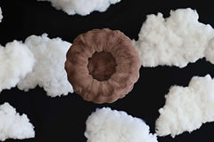 Minky Couture Milk Chocolate Pet Bed surrounded by fluffy clouds, showcasing its circular and cozy design.