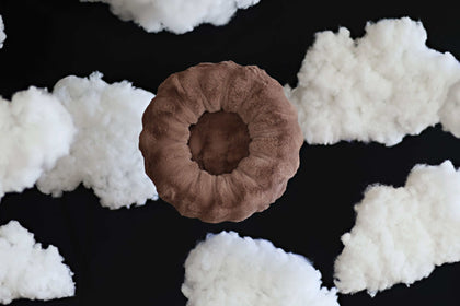 Minky Couture Milk Chocolate Pet Bed surrounded by fluffy clouds, showcasing its circular and cozy design.