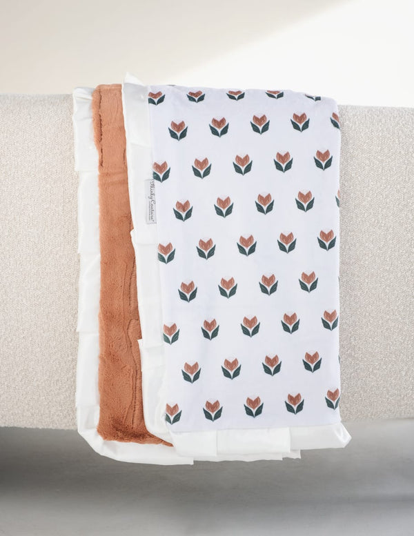 Tulip Garden Blanket displayed with a cream background and tulip pattern, featuring a hazelnut plush backing and evergreen ruffle.