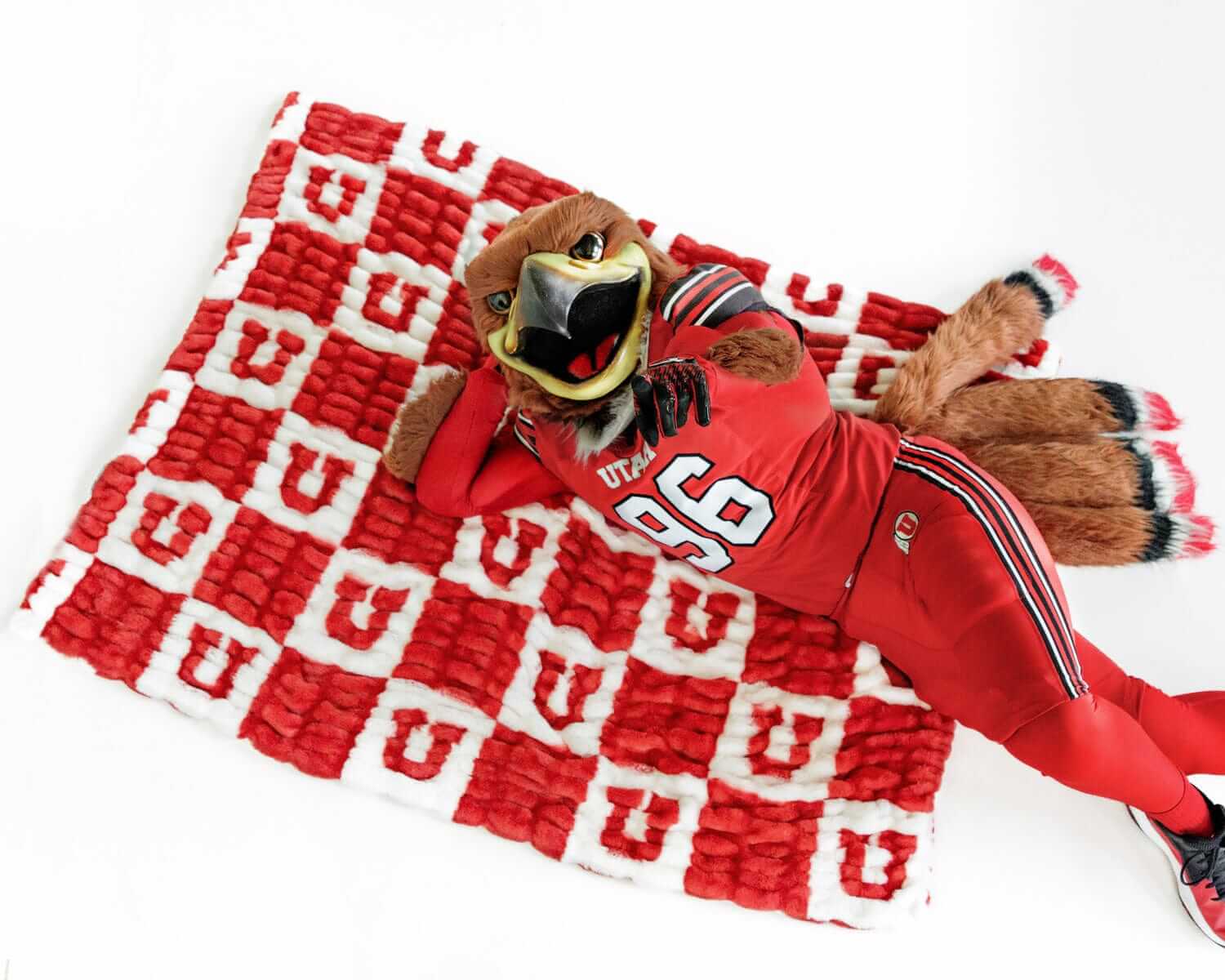Minky Couture University of Utah Utes Blanket with mascot lounging on red and white checkered design.