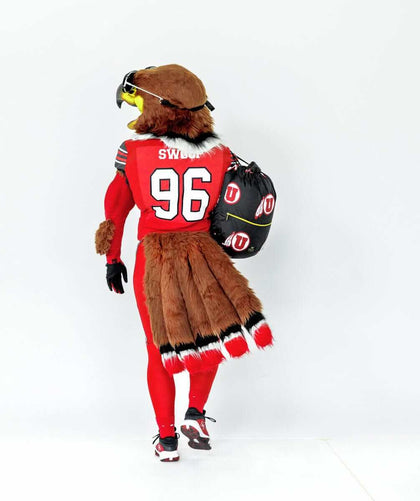 Eagle mascot in red 96 jersey carrying black U logo blanket bag on white background.