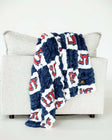 Blue and white Utah Tech Trailblazerscheckered plush blanket draped over light gray sofa indoors.