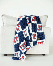 Blue and white Utah Tech Trailblazerscheckered plush blanket draped over light gray sofa indoors.