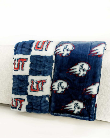 Navy and white Utah Tech Trailblazers logo blanket draped over light gray chair.