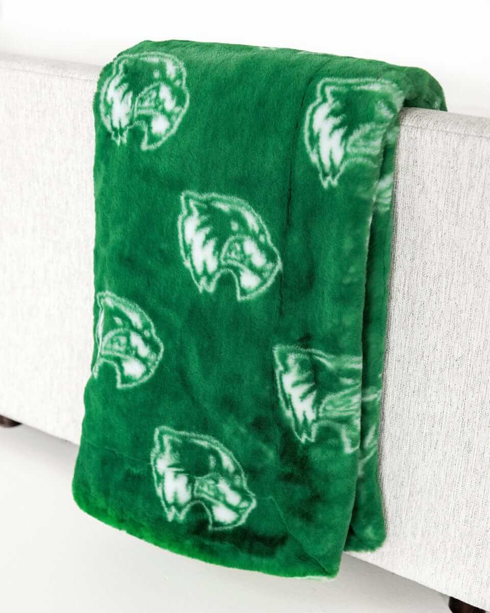 Green Utah Valley Wolverines blanket with repeating logo pattern draped over a bench.