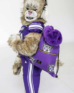 Weber State Wildcats mascot holding purple blanket and matching pillow in studio setting.