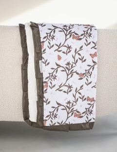 Peony Garden Blanket draped elegantly, featuring floral peony pattern and olive satin ruffle, perfect for nurseries.