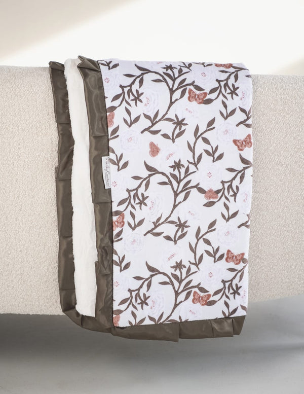 Peony Garden Blanket draped elegantly, featuring floral peony pattern and olive satin ruffle, perfect for nurseries.