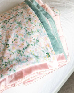 Minky Couture Blushing Blue blanket with a pattern of pink flowers on a misty blue background.