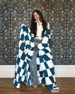 Hugs Check Blue Blanket draped stylishly, featuring a checkered pattern of navy and white squares.