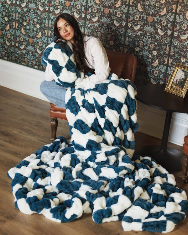 Hugs Check Blue Blanket displayed with a model, showcasing its plush navy blue and white checkered design.