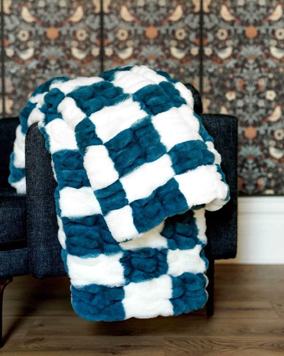 Hugs Check Blue Blanket draped over a chair showcasing its plush checkered design in navy blue and white.
