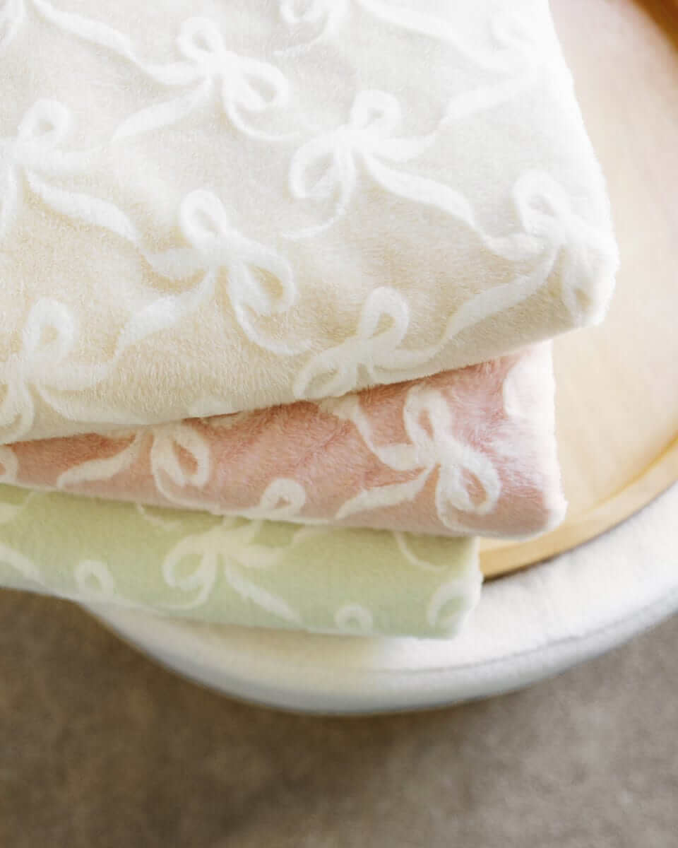 Bows Sand Blanket displayed in soft hues, featuring an embossed bow pattern for added elegance and charm.