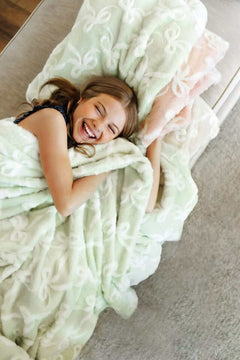 Bows Sand Blanket, a cozy plush blanket, brings warmth and joy to relaxation with its elegant design.
