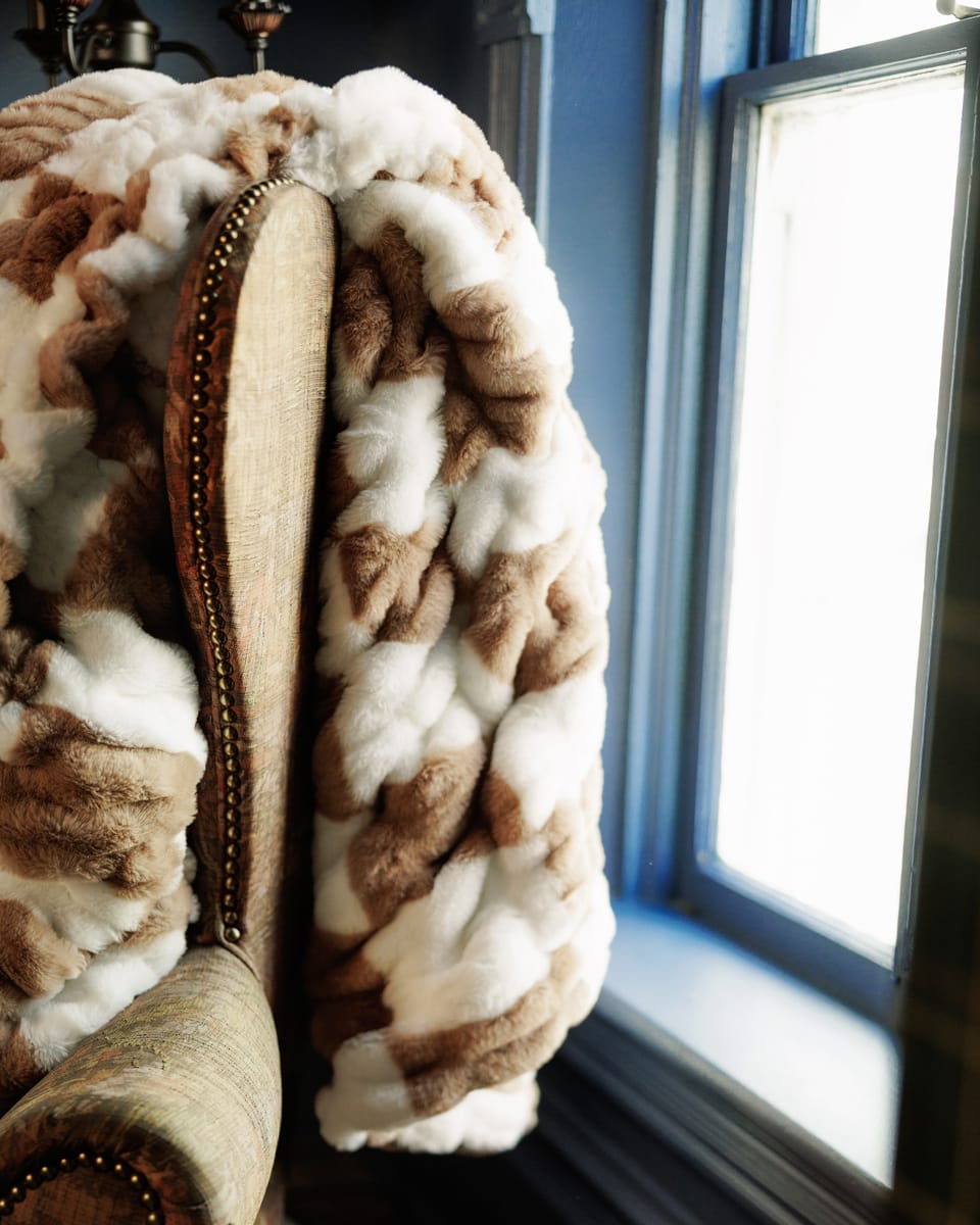 Hugs Check Milk Chocolate Blanket draped over a chair, showcasing its soft, checkered pattern and inviting comfort.