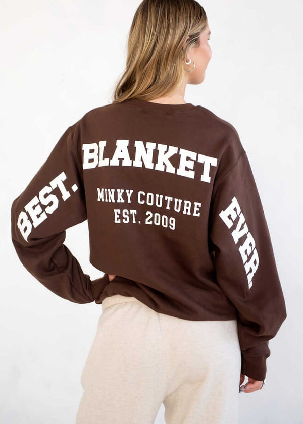 Person wearing a brown Minky Couture sweatshirt with “Best Blanket Ever” text on the back.