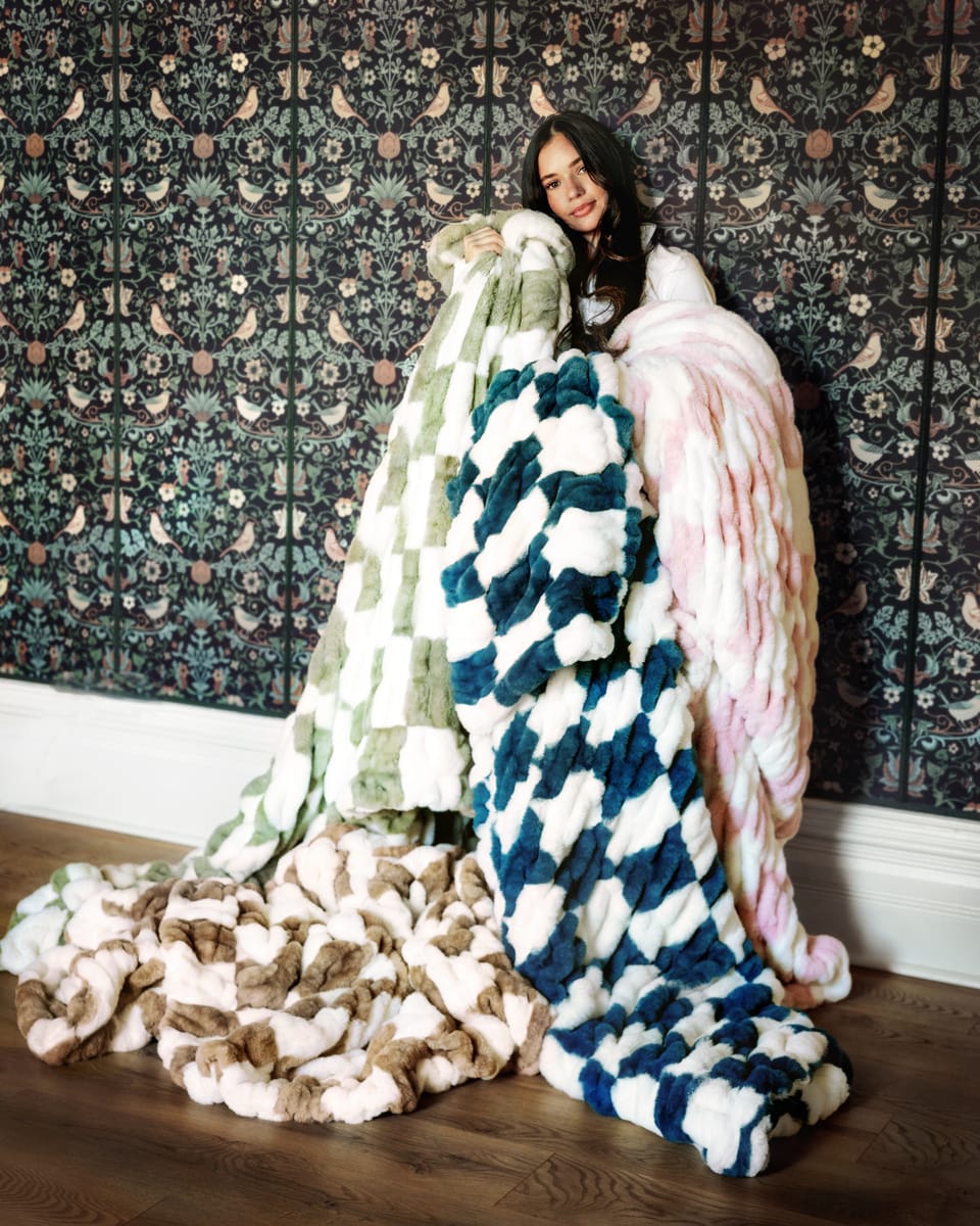 Woman showcasing multiple colorful plush Minky Couture Hugs Check Blankets.