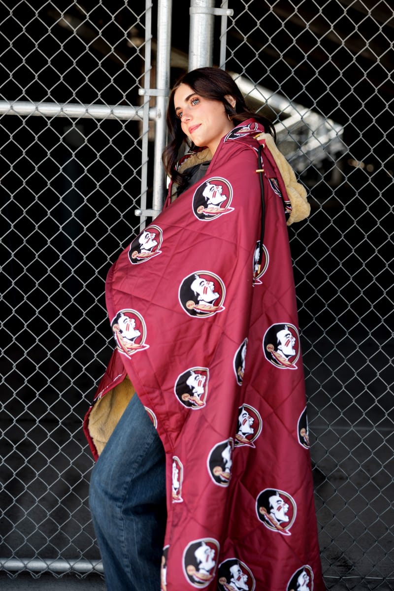 Florida State Seminoles Hooded Stadium Everywhere Blanket draped over a woman by a chain link fence.