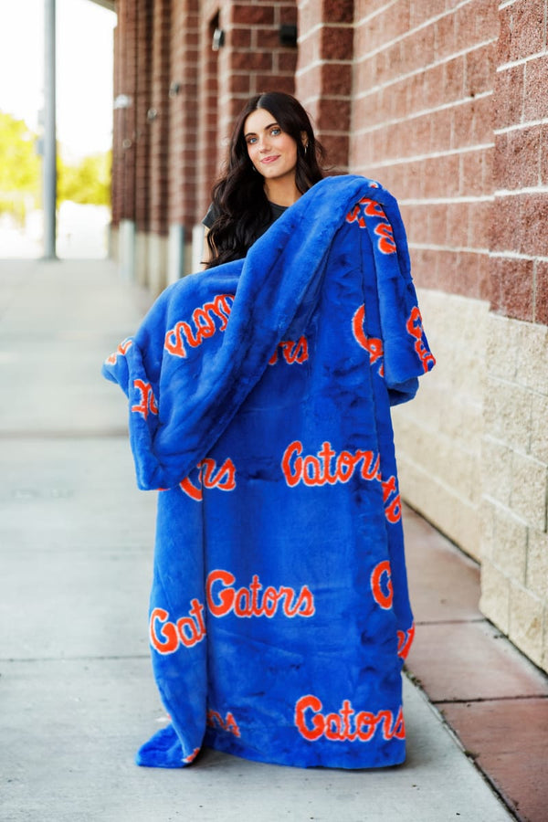 Florida Gators Blanket draped on a smiling woman standing outside, showcasing team spirit and cozy softness.