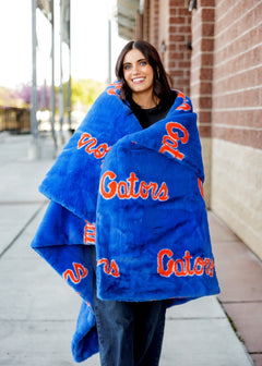 Florida Gators Blanket wrapped around a smiling woman showcasing team spirit outdoors.