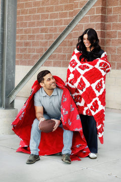 Hugs University of Wisconsin Badgers Blanket keeping two friends cozy during a game day.