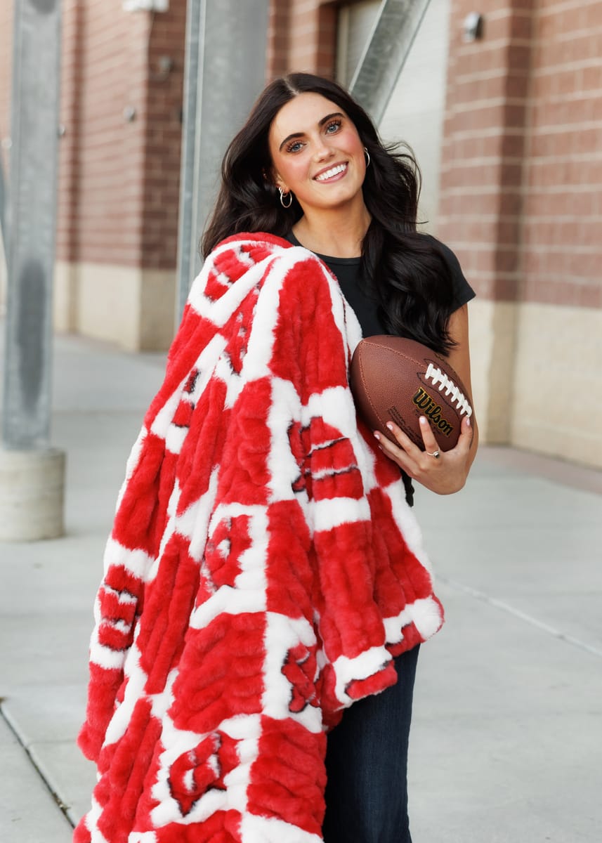 Student showcasing the University of Wisconsin Badgers Blanket while holding a football, perfect for game day.