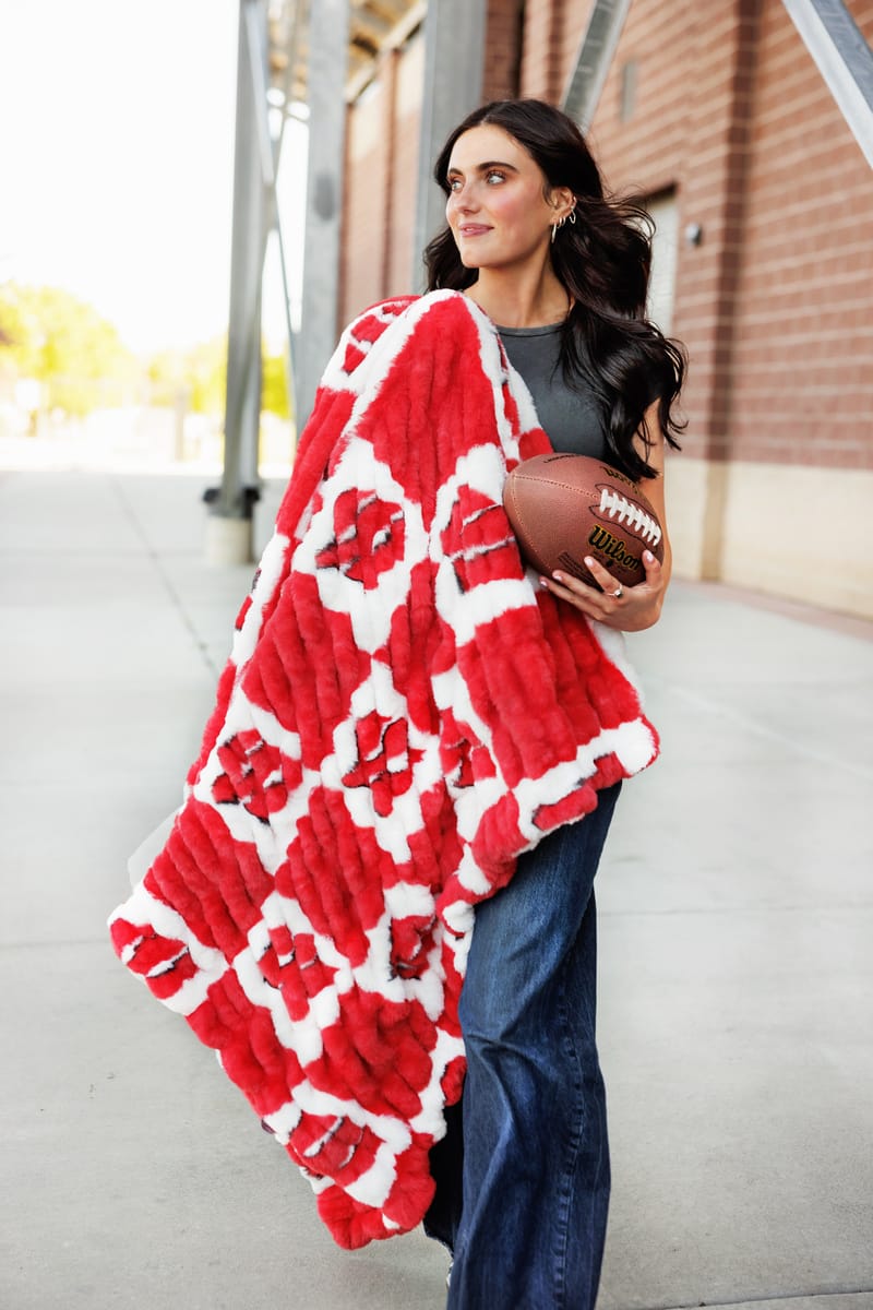 University of Wisconsin Badgers Blanket cozy blanket with checkered logo pattern held by woman outdoors.