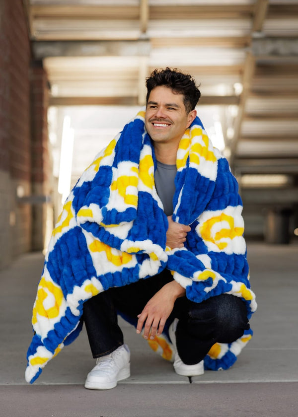 Young man wearing the University of Pittsburgh Panthers Blanket, cozy and stylish in deep navy and bright yellow.