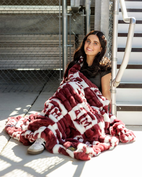 Texas A&M Aggies Blanket wrapped around a person, showcasing the soft maroon checkered design.