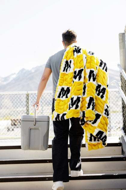 Person carrying University of Missouri Tigers Blanket while walking up stairs on a sunny day.