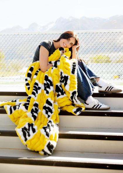 A young woman wrapped in a University of Missouri Tigers Blanket, showcasing school spirit on the bleachers.