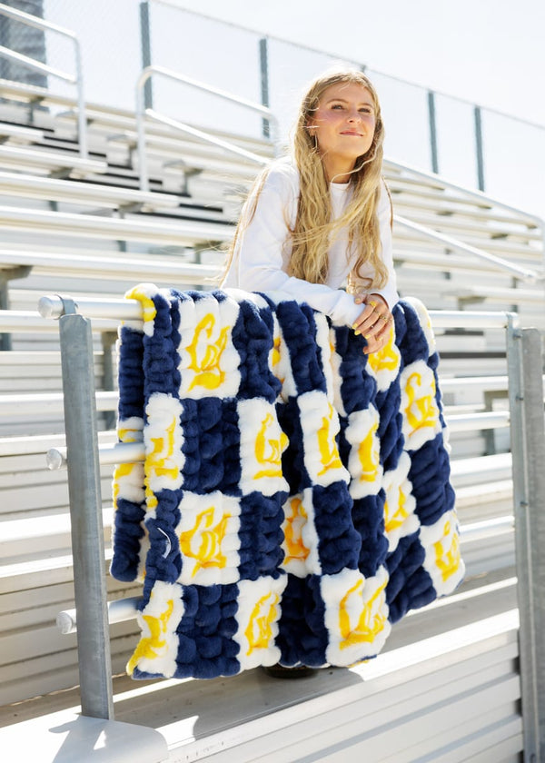 Hugs Cal State Berkeley Bears Blanket draped over a person sitting in bleachers, showcasing school spirit and comfort.