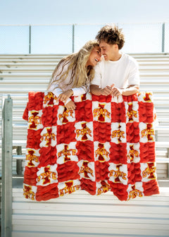 Couple snuggled in Iowa State Cyclones Blanket enjoying game day at the stadium with a vibrant checkered design.