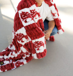 Hugs Washington State Cougars Blanket draped over a person, showcasing a plush crimson checkered logo design.