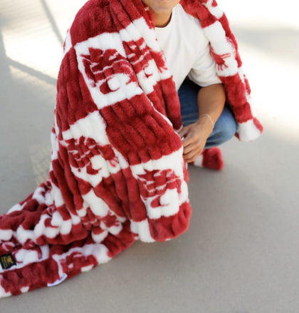 Hugs Washington State Cougars Blanket draped over a person, showcasing a plush crimson checkered logo design.