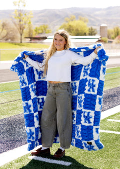 University of Kentucky Wildcats Blanket model displaying plush blue checkered blanket outdoors.