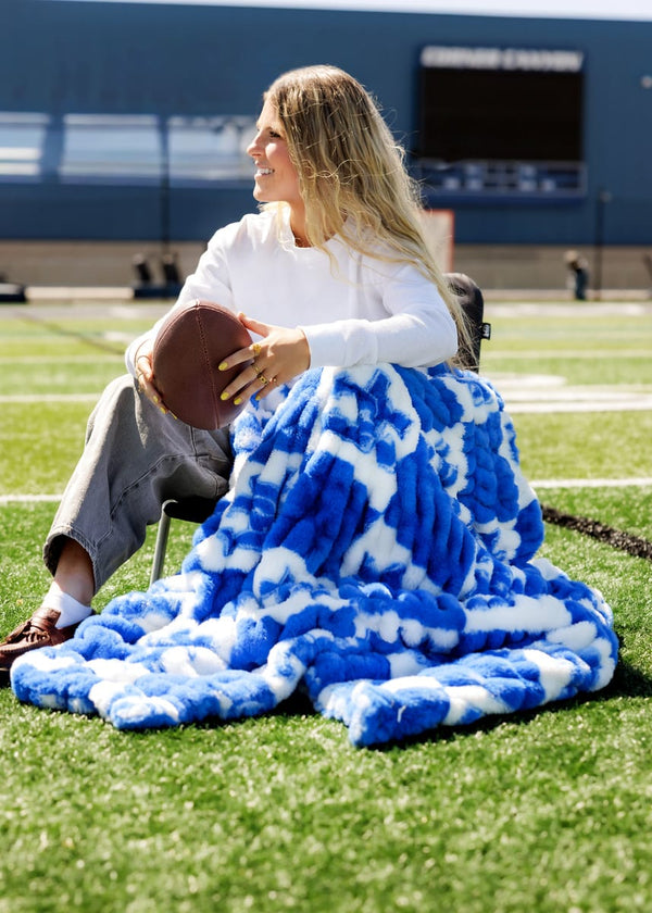 University of Kentucky Wildcats Blanket wrapped around woman sitting on a football field holding a football.